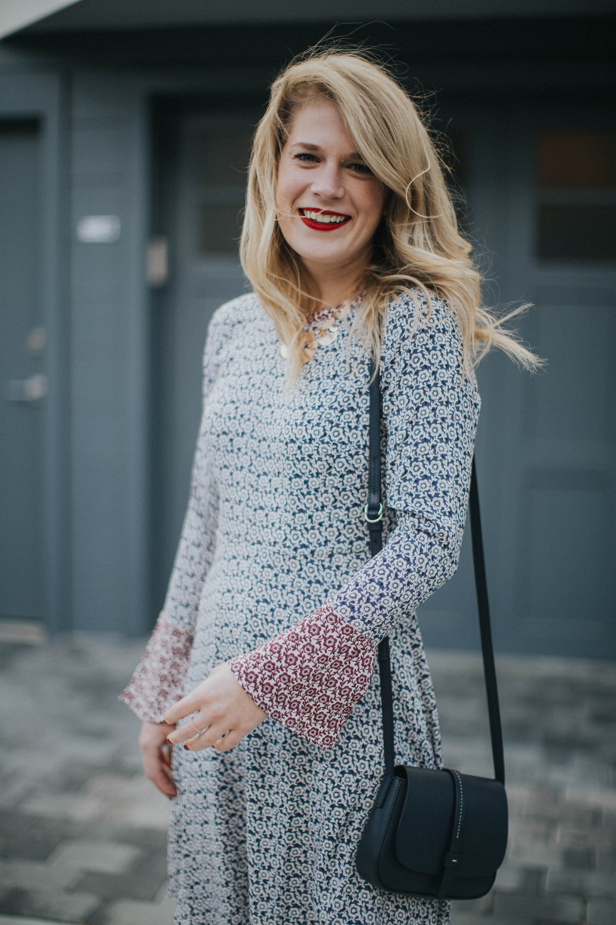 Blogger Cait Weingartner of Pretty & Fun wearing a LOFT floral bell sleeve dress with M. Gemi sandals and a BaubleBar statement necklace.